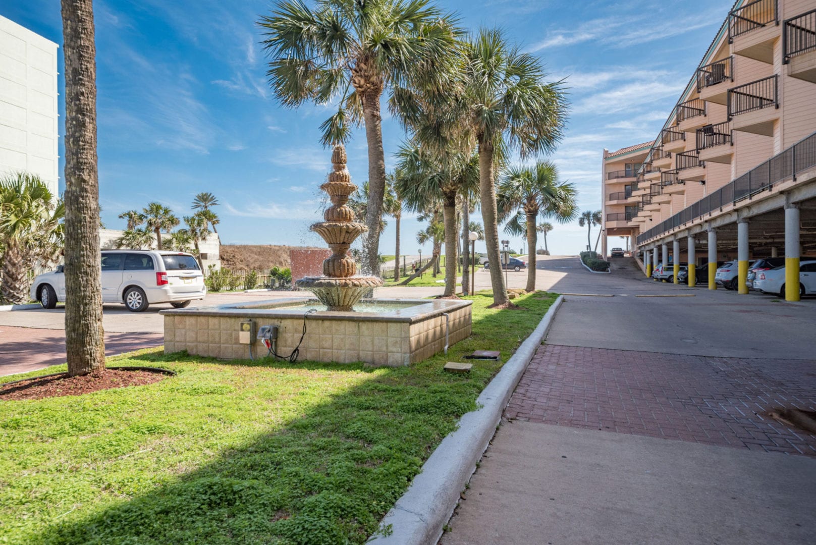 A fountain on the side of a road near palm trees.